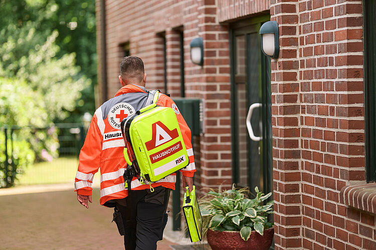 Hausnotruf Mitarbeiter geht auf Haus zu